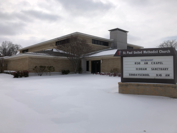 St. Paul United Methodist Church, ein Gebäude mit Fenstern und Türen, umgeben von Pflanzen und Bäumen, mit Schnee auf dem Boden und einem bewölkten Himmel im Hintergrund, mit einer Tafel mit etwas Text darauf auf der rechten Seite.