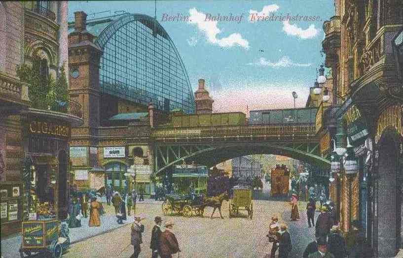 Alte Postkarte zeigt eine belebte Berliner Straße mit Fußgängern, Pferdewagen, Gebäuden, Laternen, einer Brücke und einem bewölkten Himmel, mit Text oben.