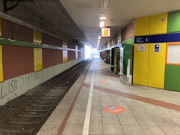 Ein Bahnsteig mit einem Zug auf den Schienen, beleuchtet von Deckenlampen, mit Graffiti an einer linken Wand und einigen Gegenständen auf der rechten Seite, identifiziert als Berlin Hauptbahnhof in Berlin, Deutschland.