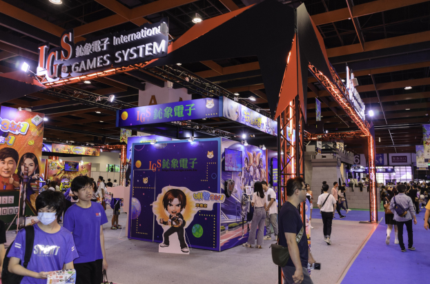 Eine Gruppe von Menschen, die durch einen Konferenzsaal auf einer Gaming-Messe in China gehen, einige tragen Taschen und halten Gegenstände, mit Displaytafeln, Deckenbeleuchtung und Teppichboden.