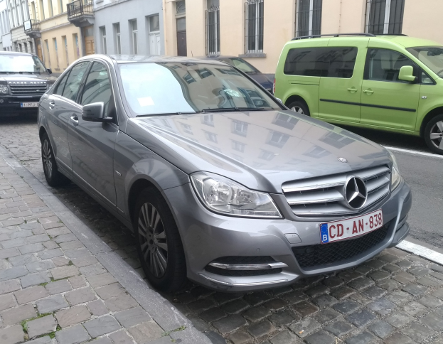 Mercedes-Benz C 220 CDI BlueEfficiency Avantgarde fährt auf einer Straße mit Gebäuden, Fenstern, Geländern und Namensschildern im Hintergrund unter einem sichtbaren Himmel.