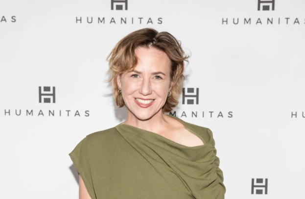 Eine Frau in einem grünen Kleid, die auf einem roten Teppich lächelt