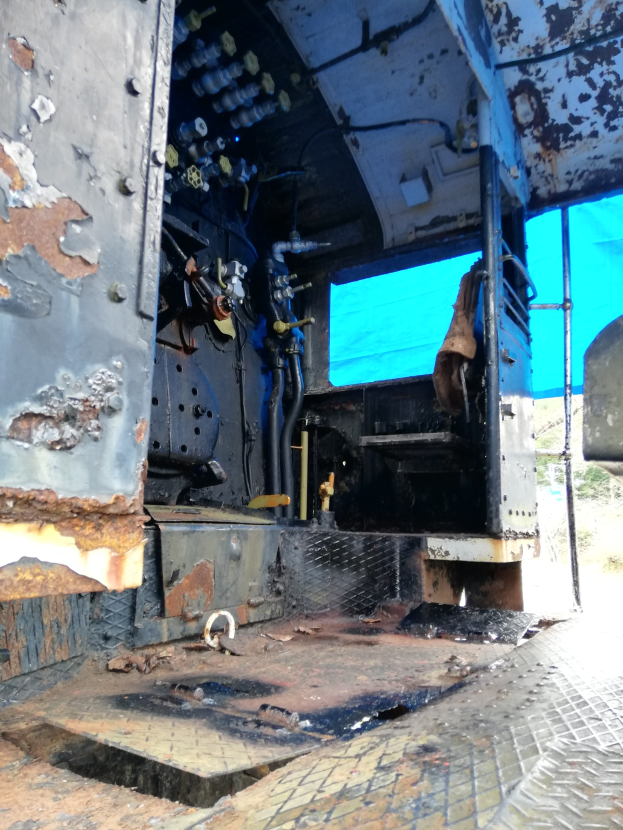 Ein verrostetes, heruntergekommenes Truck-Interieur mit sichtbaren Gebrauchsspuren vor Bäumen und einem klaren blauen Himmel.
