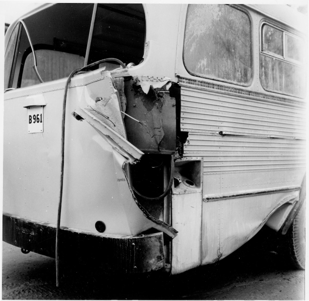 Schwarzes und weißes Foto eines Busses mit schwerer Frontschäden nach einem Autounfall auf der Straße.