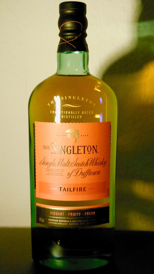 Tiefe bernsteinfarbene Flasche Singleton of Dufftown Tailfire Single Malt Scotch Whisky mit einem schwarzen Etikett, das eine Löwen- und Burgwappen zeigt.