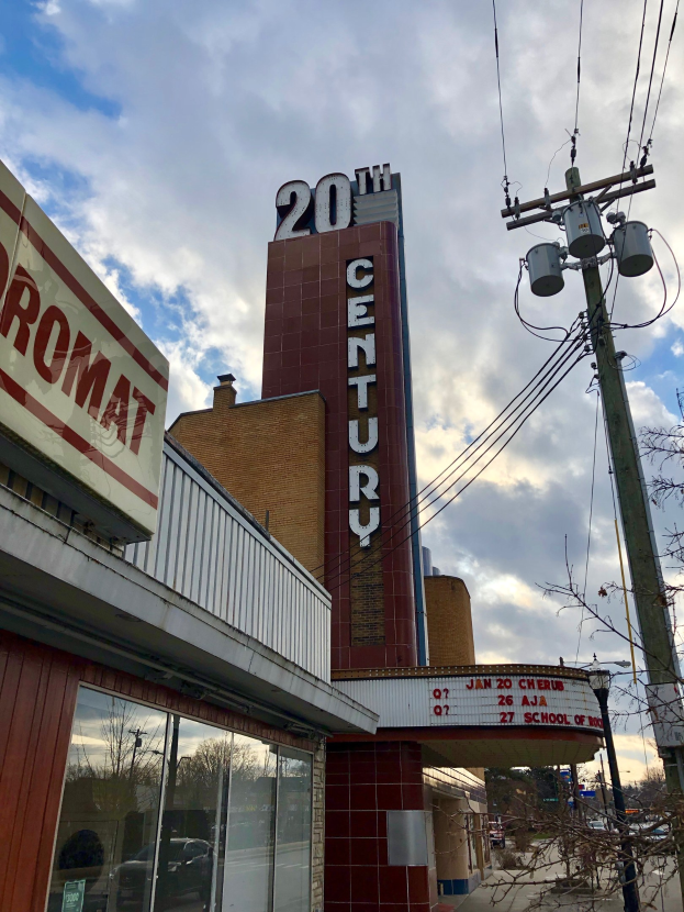 Das 20. Jahrhundert Theater in Detroit, Michigan, ein glaswälliges Gebäude mit Namensschildern, umgeben von Bäumen und Strommästen mit Drähten unter einem bewölkten Himmel.