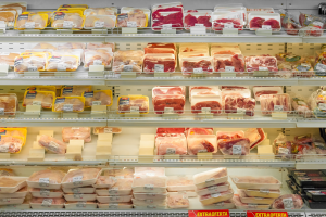 Ein gut organisierter Gem"seabteilung mit verschiedenen Fleischsorten auf Regalen, jede mit Preisschild.