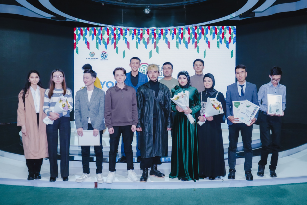 Gruppe von Menschen auf einer Bühne mit Blumensträußen und Urkunden, vor einem Hintergrund mit der Aufschrift "Jugend-Solar-Awards 2019".