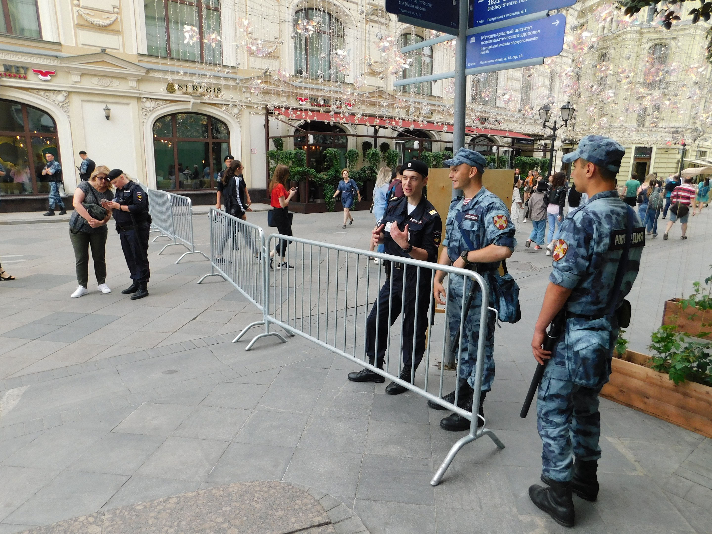 Polizeibeamte in Uniform stehen hinter Absperrungen und blicken einer Menge entgegen, einige halten Waffen, mit Schildern und Gebäuden im Hintergrund während einer Anti-Terror-Operation in Wien, Österreich.