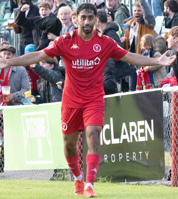 Ein Fußballspieler in roter Uniform rennt mit ausgebreiteten Armen auf einem Feld, im Hintergrund eine Zuschauermenge und ein Banner mit der Aufschrift "Middlesbrough FC v Swansea City - Sky Bet Championship".