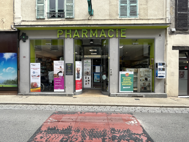 Apotheke mit Glaswänden und -türen, Plakate an den Wänden, befindet sich an einer Straßenecke mit einer Straße unten.