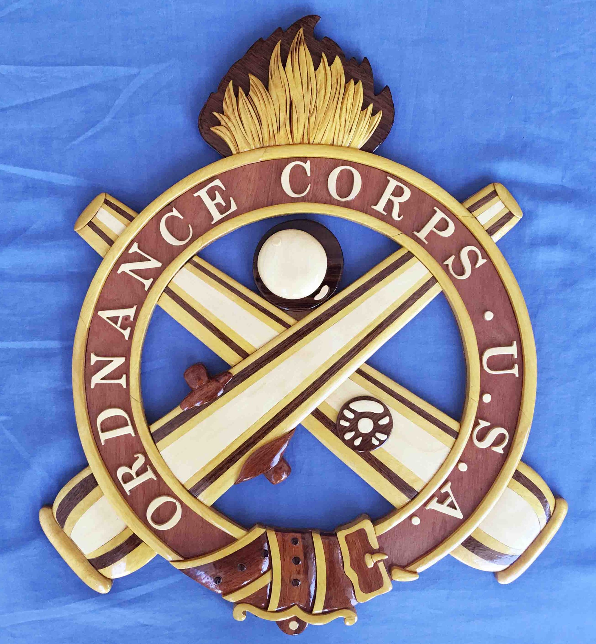 Holzschild mit 'Ordnance Corps'-Text, verziert mit einer geschnitzten Darstellung eines weißen Sterns auf einem navyblauen Hintergrund mit goldener Umrandung, auf blauem Tuch montiert.