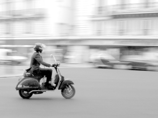 Eine Person fährt Scooter auf einer Straße.