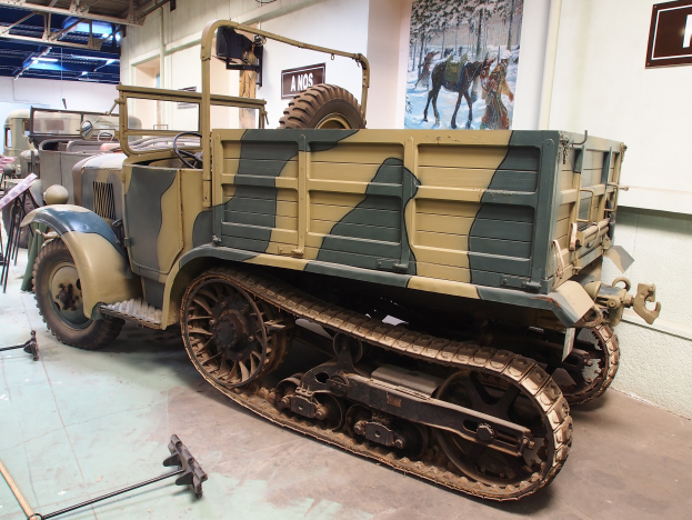 Alter militärischer M3A1-Spähwagen im Museum ausgestellt, umgeben von anderen Fahrzeugen und Informationsanzeigen.
