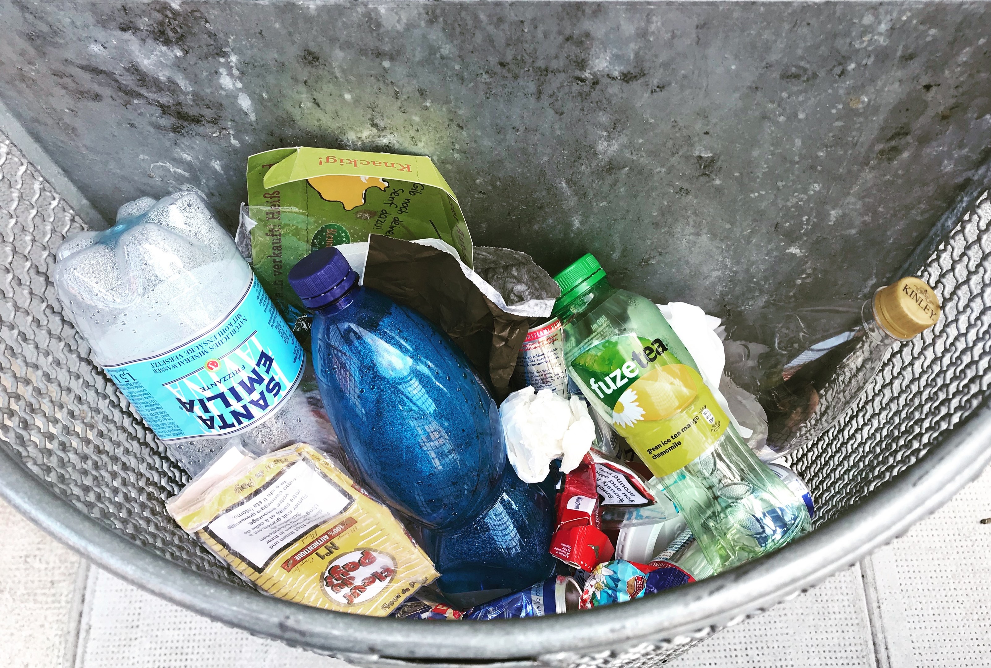 Metallmöbelfall mit verschiedenen Kunststoffflaschen, Tüten und anderen Abfällen.