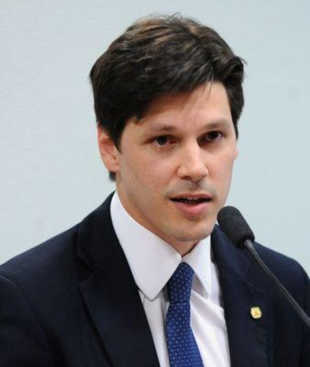 Ein Mann im Anzug spricht an einem Rednerpult mit einem Mikrofon zu einer Menge hinter einem Banner, wahrscheinlich über ein Regierungssozialmedienverbot.