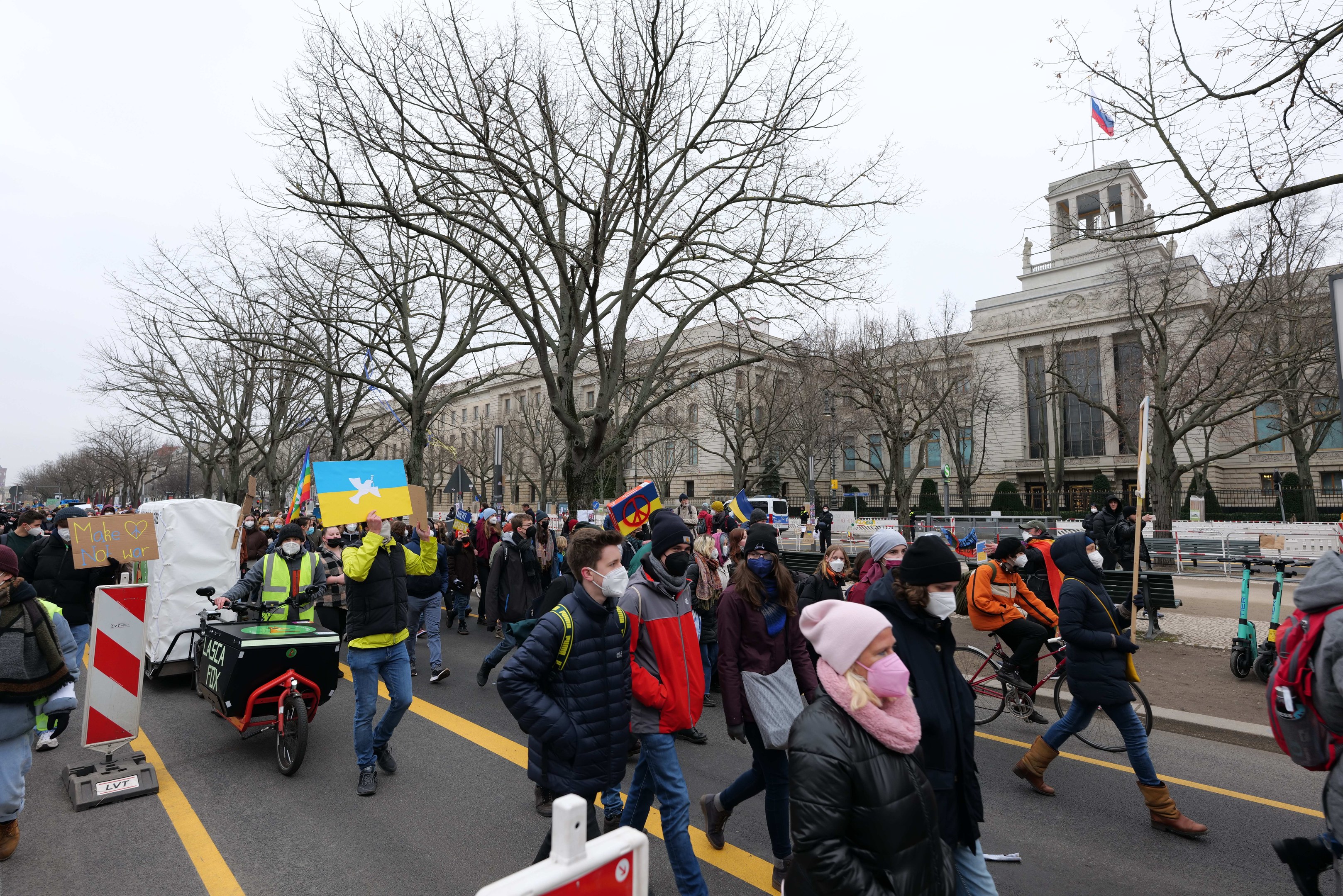 Eine große Gruppe von Menschen nimmt an einer Protestdemo in Washington, D.C. am 21. Januar 2020 teil und marschiert eine Straße entlang mit Schildern, Bannern und Fahrrädern vor einer Kulisse aus Schildern, Bäumen und einem klaren blauen Himmel.