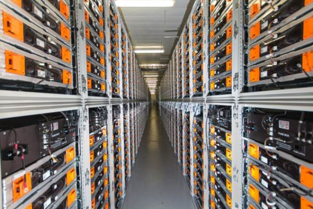 Eine lange Reihe von Servern in einem Datenzentrum mit elektronischen Geräten in den Racks und Lampen oben.