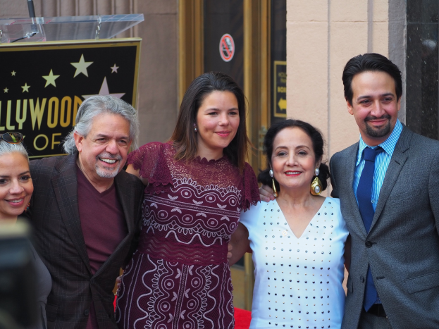 Gruppe von Menschen auf dem roten Teppich bei der Zeremonie des Hollywood Walk of Fame posierend, mit einer Tafel, Glaspodest und Wand im Hintergrund.