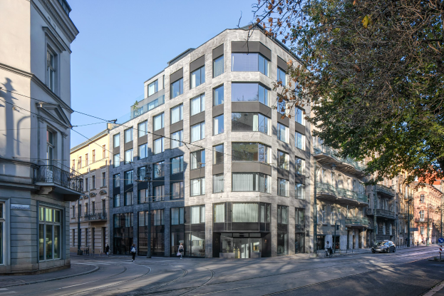 Großes Bürogebäude mit zahlreichen Fenstern, umgeben von Straßeninfrastruktur, Fahrzeugen, Fußgängern, Bäumen und einem bewölkten Himmel, als neuer Firmensitz.