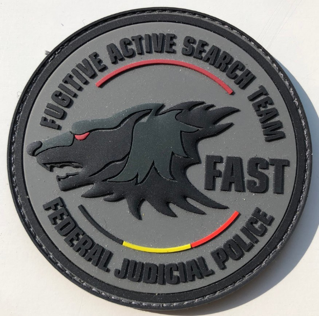 Weiße Fläche mit einem schwarzen kreisförmigen Logo, das einen weißen "F" enthält und zentrierte schwarze Schrift mit dem Text "Fugitive Active Search Team Fast Federal Judicial Police".