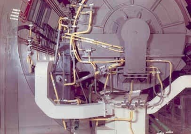 Großes industrielles Accelerator-Gerät mit mehreren angeschlossenen Komponenten und Kabeln innerhalb eines Gebäudes.