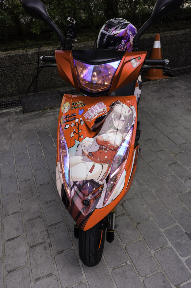 Ein oranger E-Scooter auf einer Straße geparkt mit einem Helm darauf, einer Verkehrskegel, einer Wand und Bäumen im Hintergrund.