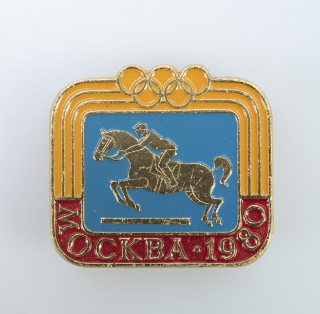 Olympische Spiele-Badge mit einer Person in weißem Hemd und blauen Shorts, die ein kastanienbraunes Pferd mit weißer Mähne und Schweif reitet, vor einem hellblauen Himmel mit weißen Wolken, wahrscheinlich von den Olympischen Winterspielen 1988.