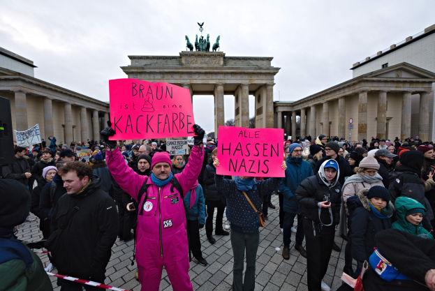 Gruppe von Demonstranten versammelt sich vor dem Brandenburger Tor in Berlin und hält Schilder gegen die Anti-Nazis-Bewegung der deutschen Regierung.