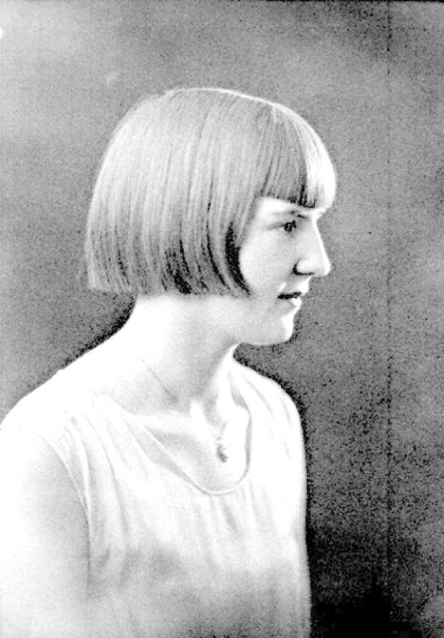 Ein Schwarz-Weiß-Foto einer Frau mit einem kurzen Bob-Haarschnitt, ihr Gesicht ist deutlich zu erkennen, mit zur Seite schauenden Augen und leicht geöffneten Lippen.
