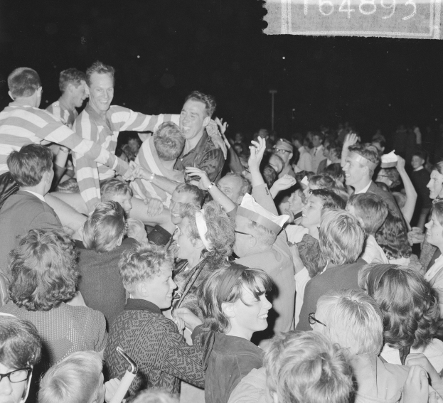 Schwarzes und weißes Foto einer Menge bei einem Konzert mit Menschen, die in der Mitte zusammenstehen und Text in der oberen rechten Ecke.