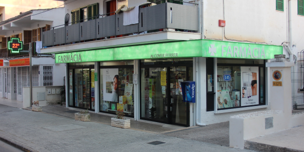 Eine Straßenansicht einer Apotheke mit umliegenden Gebäuden, Fahrzeugen und einem klaren blauen Himmel.
