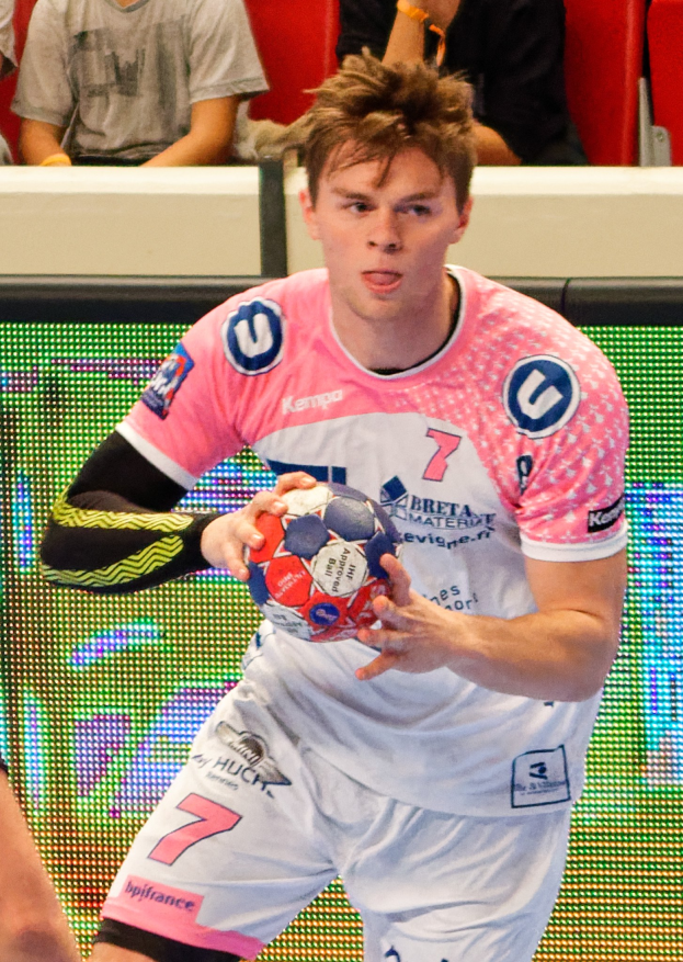 Männer bei einem Handballspiel auf einem Feld während des Futsal-Weltmeisterschafts 2019 zwischen Bayern München und Paris Saint-Germain, mit Zuschauern im Hintergrund.